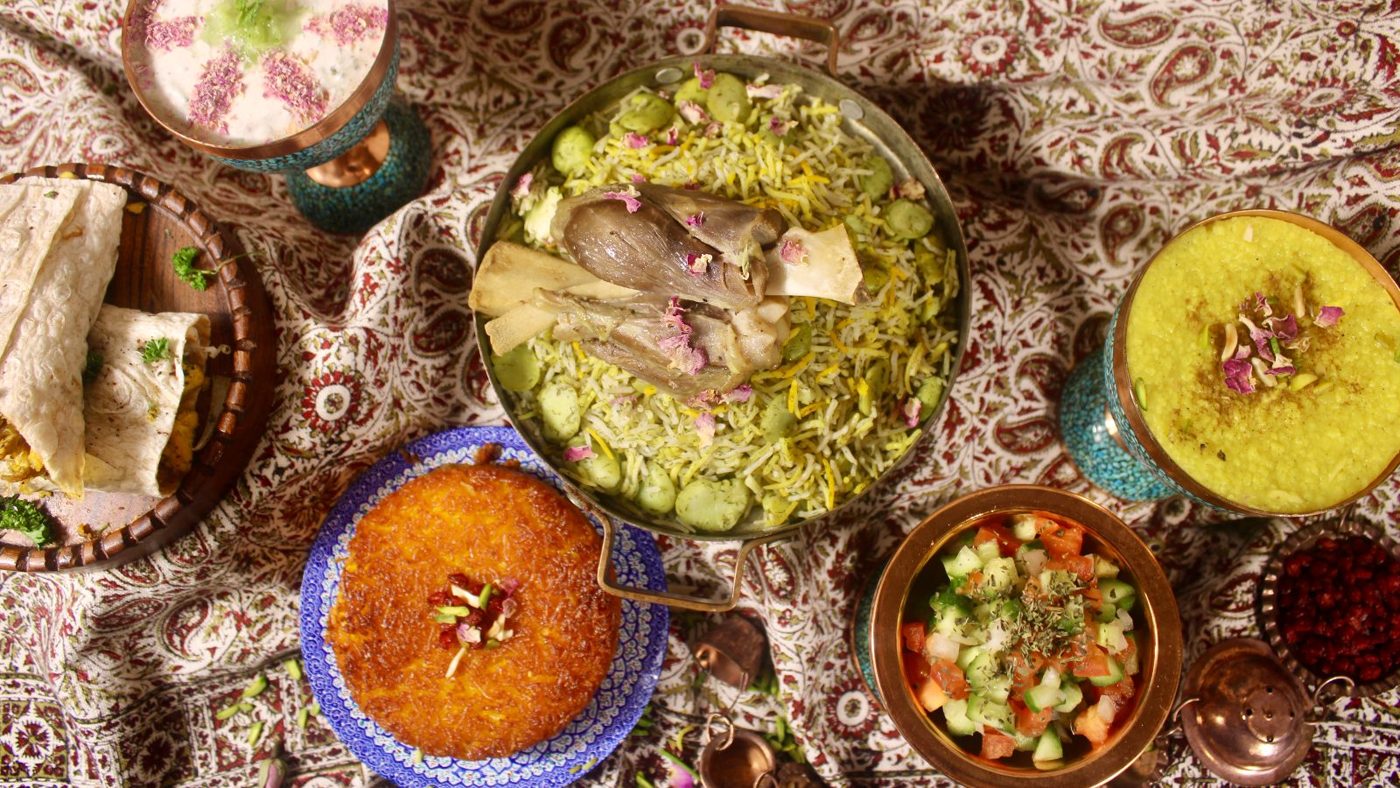 A Persian spread: saffron tahchin, dill rice with lamb, Shirazi salad and lavash on a patterned cloth